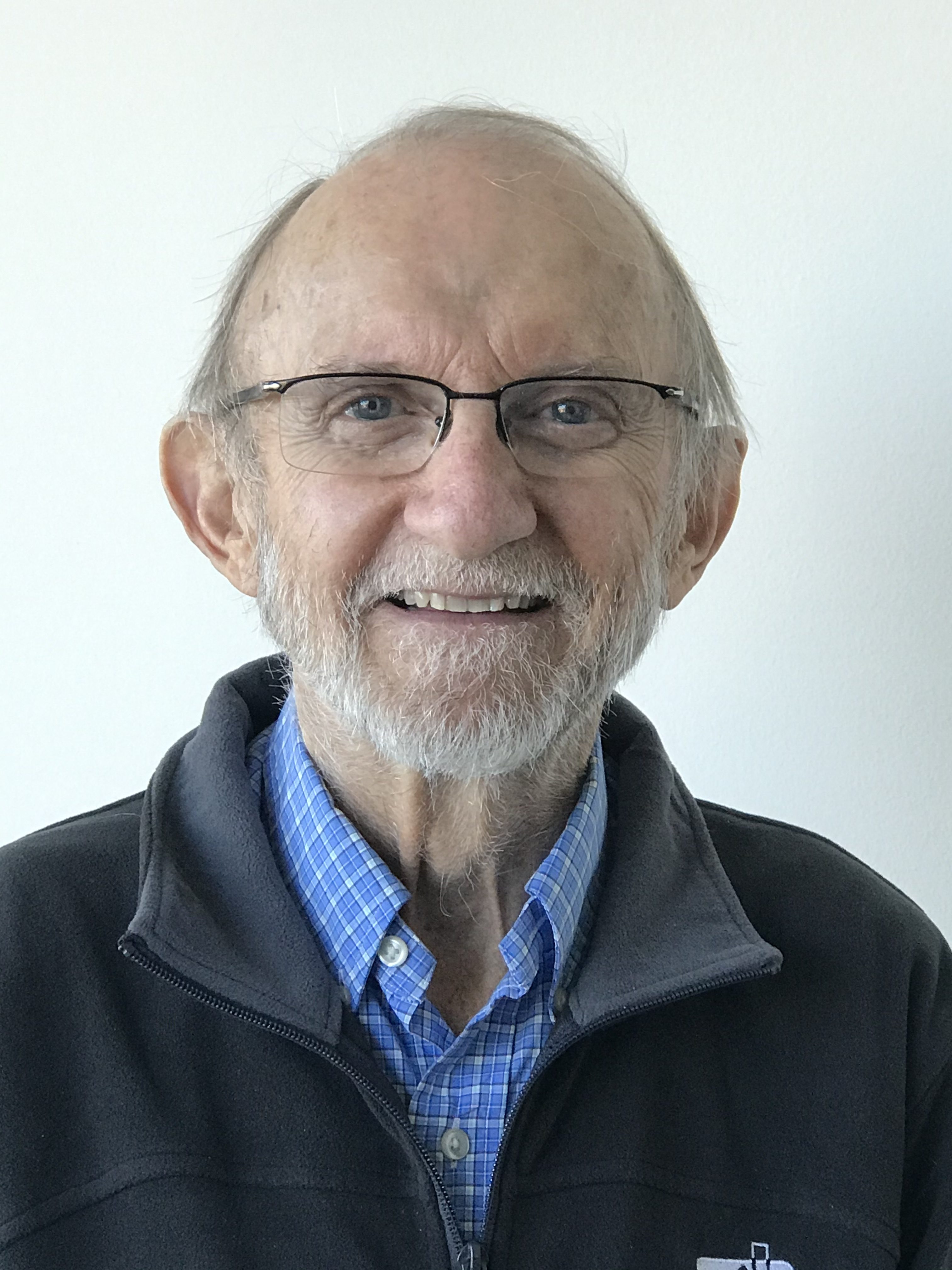 Portrait de Jim Dadson. Jim, un homme âgé avec une barbe blanche et des lunettes, sourit à la caméra.