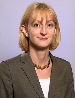 Jennifer Moore's Headshot. Jennifer has chin length blonde hair with bangs and is wearing a blazer and statement necklace.