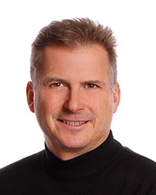 Image of man smiling, wearing black turtle neck against white background