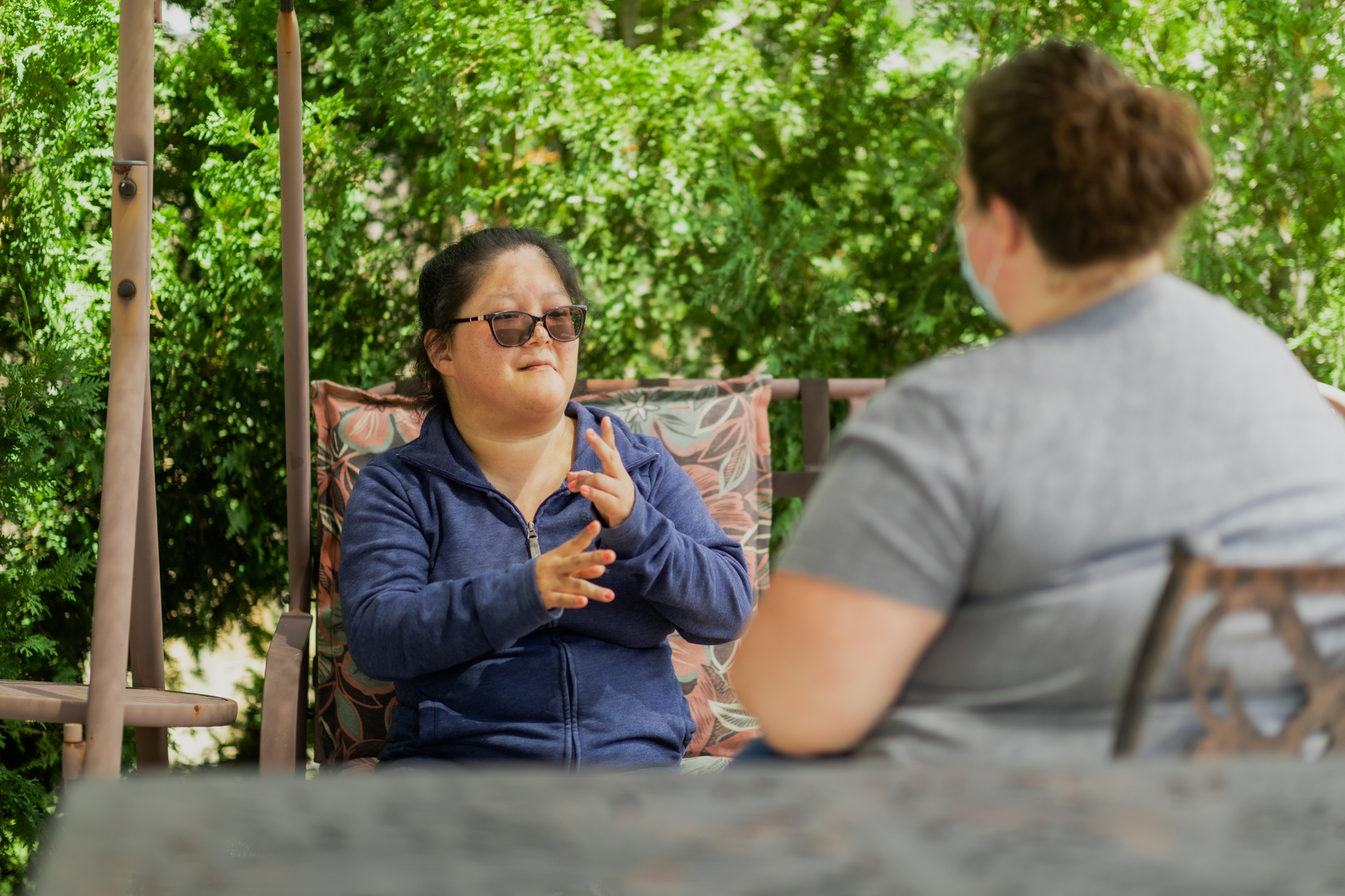 Two women seated and conversing in sign language