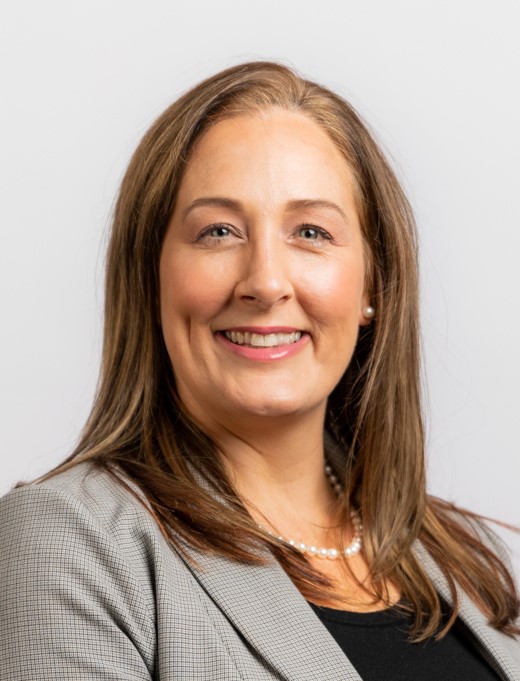 Image of woman with brown hair, light gray jacket, black shirt and pearl necklace